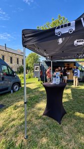 Stand Vanatipik au Festivan 2026 à Gembloux, visiteurs en discussion devant un van aménagé